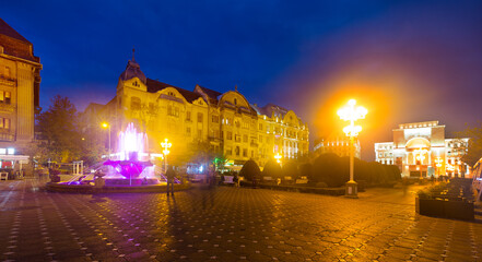 Night view of Victoriei Square with colored fountain and National Theatre and Opera, Timisoara