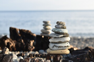 Pyramids of flat stones lie on an old wooden stump against the backdrop of the sea.