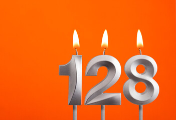 128 candle - Birthday celebration on orange background