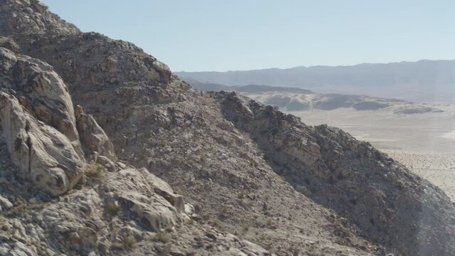 Aerial strafing across rugged mountains in Johnson Valley dry lakebed desert in Southern California
