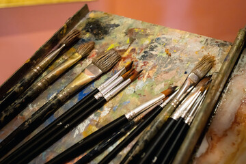 set of art brushes on palette with colorful oil stains