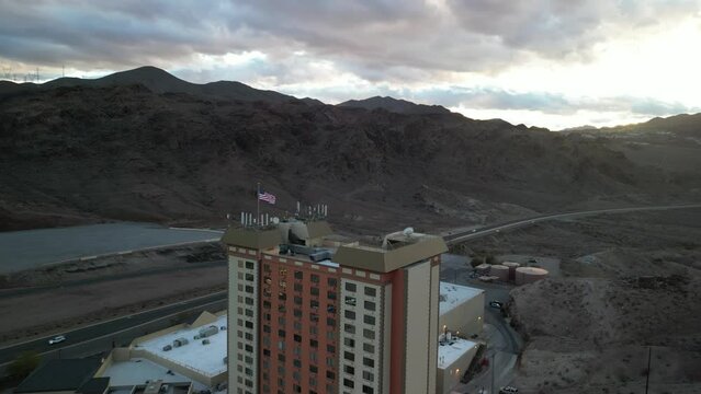 Aerial circling American flag on roof of casino in Nevada near Hoover Dam at sunset