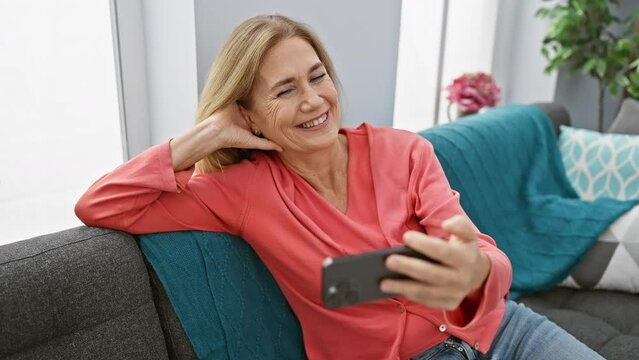 Mature woman using smartphone on couch at home