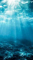 Sunlight pierces through the depths of a serene blue ocean, illuminating underwater tranquility.for themes related to marine life or the beauty of nature