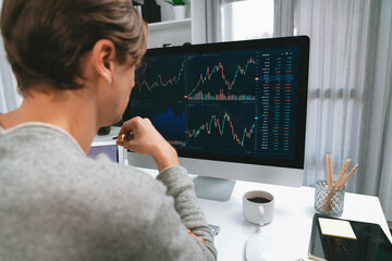 Business trader using computer and laptop to search highest profit value of dynamic increased stock market graph on working desk, analyzing exchange rate value on screen at modern office. Pecuniary.