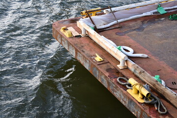 Corroded barge in choppy water. Large mooring cleats.