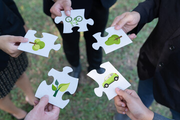 Business people or corporate partnership joining ECO friendly idea puzzle of jigsaw together as...