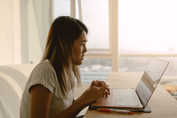 Woman in casual clothes working and typing with her computer laptop in her apartment in concept of work from home.