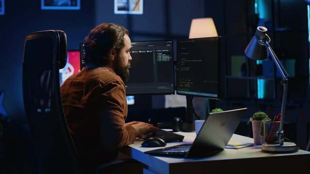 Developer pressed by deadline, drinking coffee and doing multitasking to finish developing PC code. Caffeinated IT specialist solving database error using multiple desktop and laptop screens, camera A