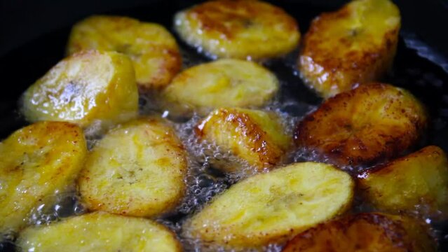 Frying ripe plantain slices in hot bubbling oil 