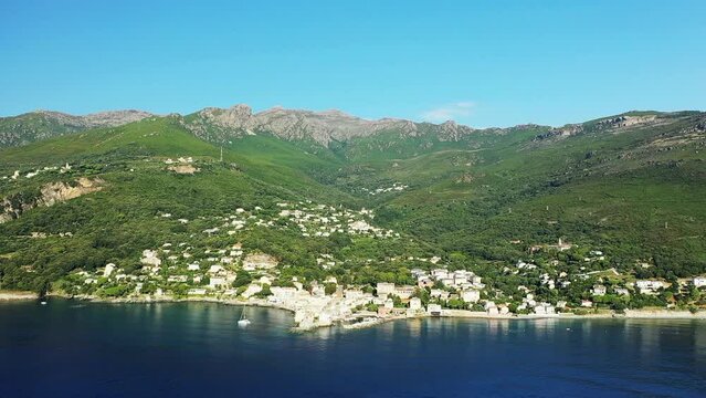 The panoramic view of the city of Erbalunga in the middle of the arid and green mountains, in Europe, in France, in Corsica, towards Bastia, by the Mediterranean Sea, in summer, on a sunny day.