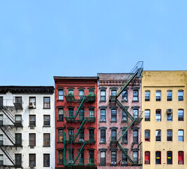 Windows on colorful brick apartment buildings with empty blue sky background in Manhattan, New York City