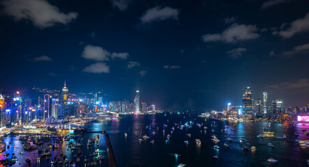 Night view of a city skyline and crowded harbor with bright lights reflecting on water