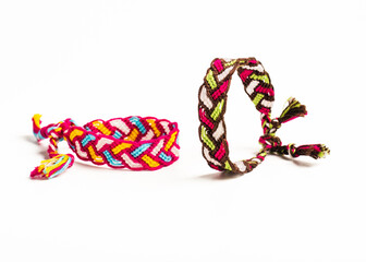Fototapeta premium Multicolored woven DIY friendship bracelets handmade of embroidery bright thread with knots isolated on white background