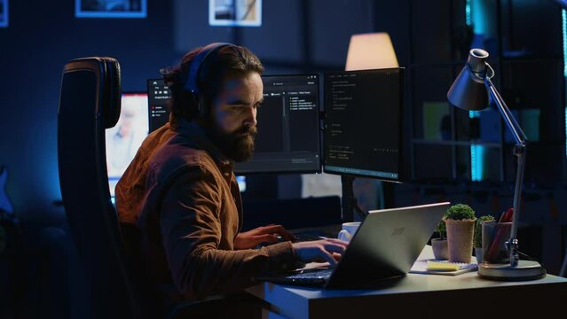 Overworked developer complaining while typing difficult code in home office, developing software application. IT expert groaning while solving coding project tasks, suffering from burnout, camera A