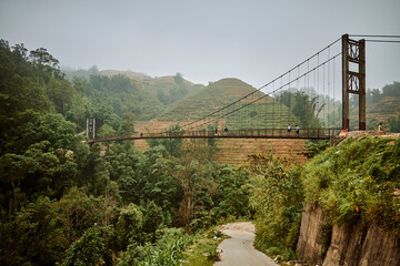 Fototapeta na wymiar bridge over river and misty jungle mountains in sapa, vietnam