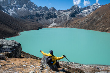 Trekker sitting on the rock and looking to the beautiful view of Gokyo lakes the sacred green lake...