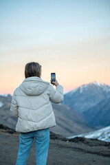 Woman taking photos in the mountains with her smartphone in winter.