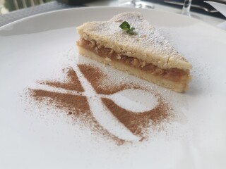 A delicious slice of cake rests on a plate, adorned with a light dusting of sweet powdered sugar.