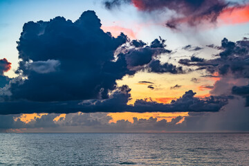 Dark storm clouds background. Dramatic dark clouds sky. Dark cloudy tropical sky at sunset sea background. Stormy cloudy sky.