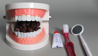 Coffee beans and tooth care tools that fill your mouth. Dental unhealthy beverage concept.
