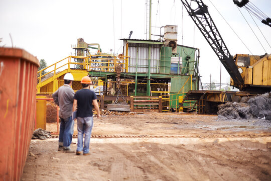 Crane, machine and engineer men in scrapyard to recycle metal for sustainability, manufacturing or pollution. Vehicle, people and outdoor in junkyard for ecology with back, industry and environment