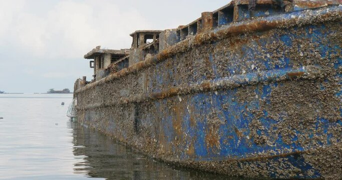  close up of the boat is heavily rusted, and barnacles and other marine life are visible clinging to its hull.
