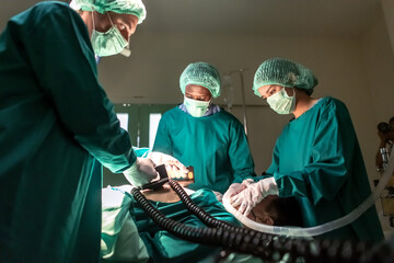 Surgeon doctor team using defibrillator with patient in operation bed 