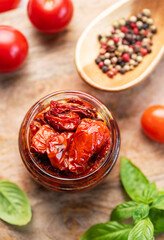 Jar with sun dried tomatoes with fresh herbs and spices.