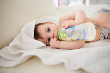 Baby, bottle and relax with boy, calm and nutrition with wellness and childcare with blanket. Home,...