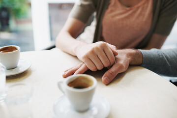 Couple, holding hands and love in coffee shop on vacation and bonding together by espresso date. Man, woman and care in restaurant with morning cappuccino, touch and romantic or support in marriage