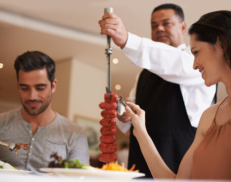 Couple, Waiter And Service For Lunch In Restaurant With Meat, Happiness And Fine Dining For Anniversary Or Honeymoon. Man, Woman And Employee With Sausage On Skewer, Healthy Meal And Table In London