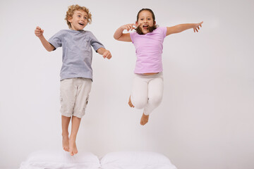 Jumping, bed and kids with fun, energy and morning in a bedroom with game and sibling. Youth, hop...