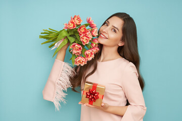 Beautiful young woman hold bouquet of tulips flowers and golden gift box, rejoices spring holiday....