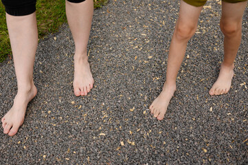 Mother and child walk barefoot along a massage eco path, on small stones in a city park.Concept of...