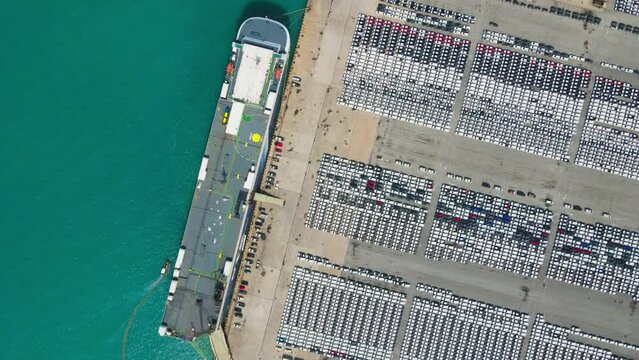 An aerial snapshot capturing the dynamic scene of a car export hub, where rows of vehicles await shipment. This stock photo showcases the organized logistics and global commerce 