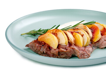 Steak with chopped apples and cinnamon in a blue plate on a white background. A festive dish with a spicy taste, close up