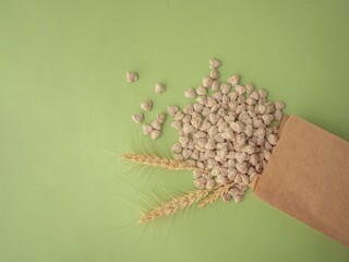 Extruded bran in the shape of a heart is poured out of the package onto a green background. Spikelets of wheat. The layout for the label. A place for the text