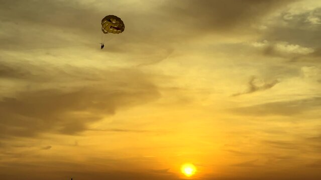 Summer beach vacation fun of parasailing during sunset