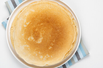 Stack of fresh thin pancakes on white table, top view