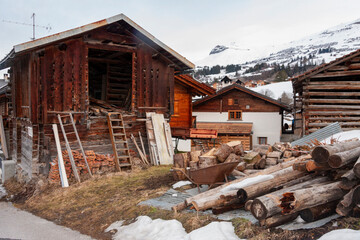 Fototapeta na wymiar Wooden Barn surrounded by firewood and timber in Obersaxen Mundaun, Graubünden, Switzerland.