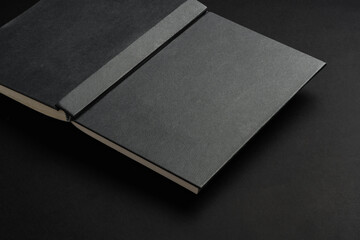 Black hardcover book or notepad mock up on black background - obrazy, fototapety, plakaty