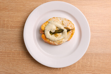 A freshly baked piece of salmon is placed on a plate and sauce is added