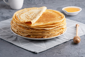 Stack of traditional russian pancakes blini on gray background with copy space. Homemade russian...