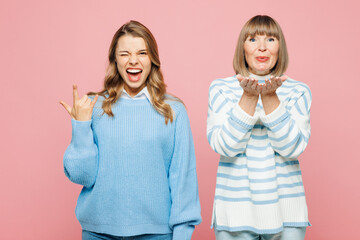 Elder parent mom 50s year old with young adult daughter two women together wear blue casual clothes do horns up gesture blow air kiss isolated on plain pastel light pink background Family day concept - obrazy, fototapety, plakaty