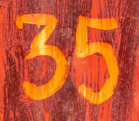 The number 35 on a rusty metal fence