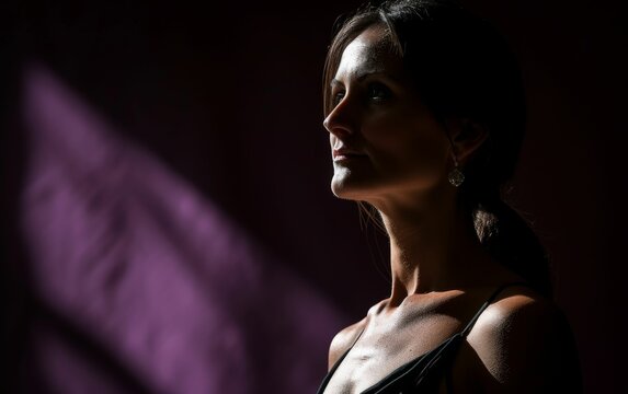 A multiracial woman standing with her eyes closed in a dark room, depicting a moment of introspection or meditation