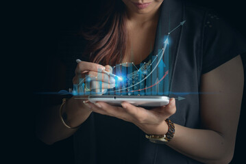 Businesswoman trader using tablet technology indicating rising trend growth in the market, long...
