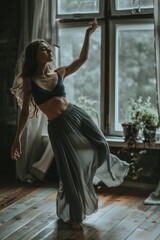 A woman is gracefully dancing in front of a window, moving fluidly and emotively as the natural light streams in