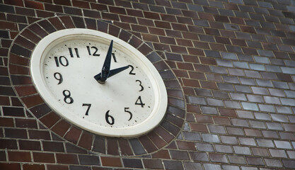Clock showing the time on an old brick wall building on a city street